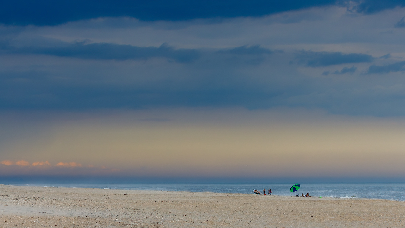 2021_05_Assateague-12774-2-CR3_DxO_DeepPRIME-Edit2048.jpg - Late in the afternoon we watched the ominous storm clouds roll in.  Pretty soon the shore was almost deserted except for these two groups of beach goers.  Not long after this picture was taken the rain came down in buckets!