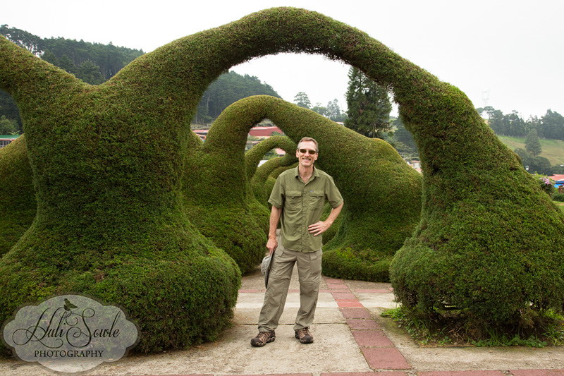 CostaRica_131.JPG - Mike posing under one of the fantastic topiaries in the square outside of the church in Zarcero.