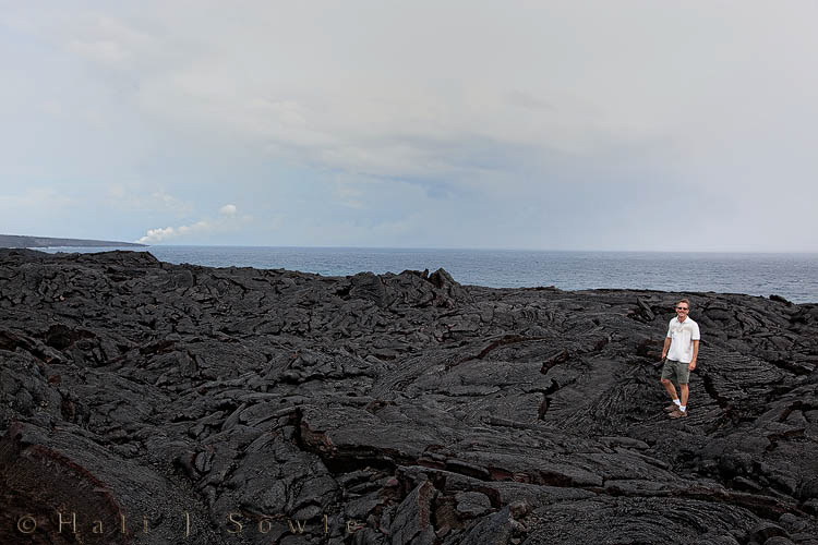2009_10_02_Hawaii-10273.jpg - Mike standing on the lava flow from the 2004-2007 eruption of Kilauea.  The steam in the background is from the current eruption where the lava is entering the ocean.