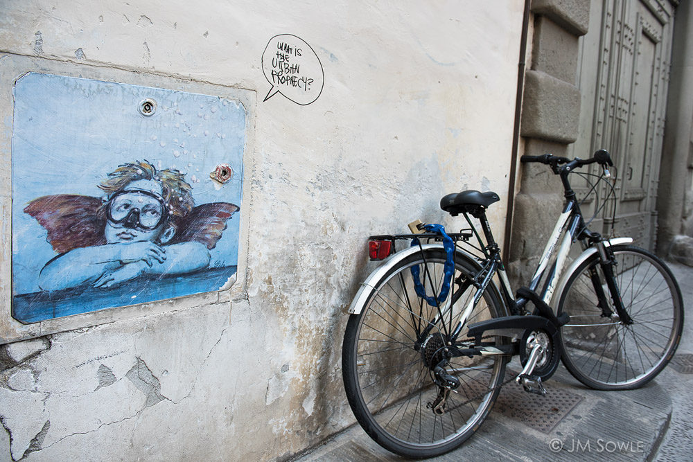 _JMS3433.jpg - There are a few things that Florence has in abundance, and two of them are in this image: creative graffiti and bicycles.  The graffiti was not really as prevalent as the bikes, but it was usually worth looking at.  The famously secretive artist "Blub" is responsible for reproducing famous works of art, with scuba masks on (Art can swim).  You can read more about Florence street art at the links below:https://www.intoflorence.com/street-art-florence/http://tianakai.com/2014/12/street-art-florence-interview-with-blub/