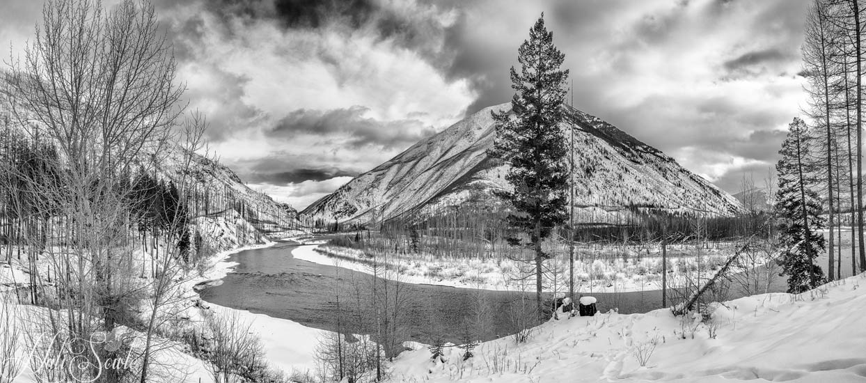 2016_01_11_Montana-10629-Pano-Edit1000-SEP2.jpg - Stitched from 2 images, this is a picture of the North Fork of the Flathead River on a snowy and cold January day.  After we finished the final morning at the Triple D we decided to go for a drive up to Glacier National Park.  How hard could that be?  Head north on Route 2 and keep going until you hit the gates of the park.  Unless you are me and decide to program it into Google Maps, just to be sure.  Google Maps decided that the entrance was off the North Fork Road.  And after driving on unpaved, un-sanded, icy narrow roads we came to the entrance... which was closed since it was the Western entrance to the park, not the main entrance.  Although a fail on the part of google maps, it provided wonderful photo opportunities and a bit of nerve wracking driving for us.  After all what's a road trip without a bit of adventure?