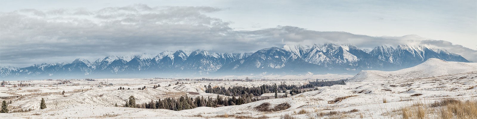 2016_01_12_Montana-10377-Pano-Edit1000.jpg - Mission Mountains from the National Bison Range.  The sky began to clear briefly in the late afternoon, revealing some of the peaks of the mountains.  This was taken from the Prairie Drive.                                                                      The National Bison Range is one of the oldest National Wildlife Refuges in the US, it was established in 1908 and contains 18,800 acres of land.  There is a small bison herd that is the focus of bison research.  The herd contains between 350 and 500 bison and was started originally with bison provided by the American Bison Society,  a group that was founded in 1905 by Theodore Roosevelt and William Hornaday (who later became the first director of the Bronx Zoo) to help save the Bison from extinction.  There are two drives in the National Bison Range.  Only the Prairie Drive is open in winter.
