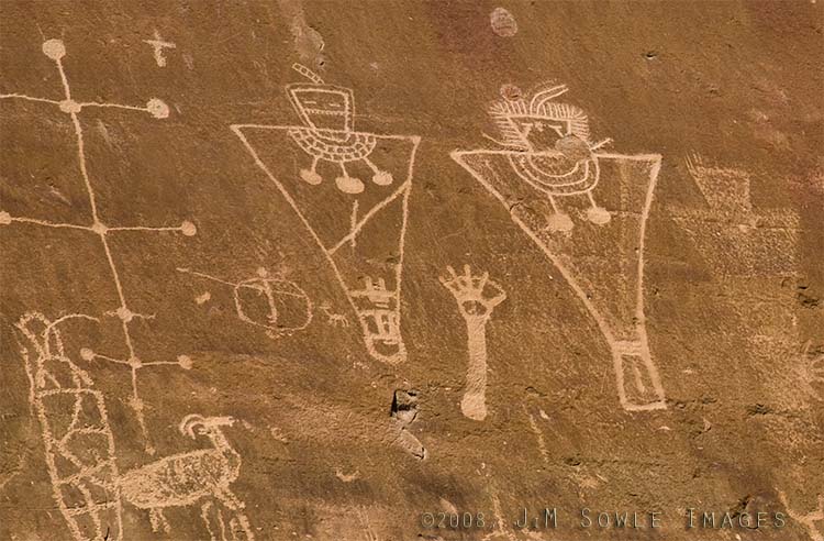 _JMS1154.jpg - This is another section of rock art from Sego Canyon.  This section has been vandalized with graffiti and bullet holes.  To diminish the efforts of those vandals, I have removed their obvious marks from this image.  The information plaque below reads as follows:The Fremont Culture thrived from about A.D. 600 to A.D. 1250, and was contemporary with the Anasazi Culture of the Four Corners area.  It is distinguished by its remarkable rock art.  Like the Anasazi, the Fremont planted corn and lived in pithouses and surface stone structures.  They constructed a distinctive basketry and made pottery.  They had a complex social structure, as is illustrated in their rock art, and were highly adaptive to the extremes of their environment.  At the top of the panel are the oldest figures.  These are the line of large red-painted figures with the rectangular bodies and small-heads, which are similar to the Anasazi Basketmaker style.  Superimposed on the older, painted figures is a line of carved (pecked) human figures.  Typically, these have trapezoids for the head and body.  The most recent Fremont period is also represented by superimposed carvings.  They are the deeply grooved outlines of two life-sized human figures with collars and waistbands, and the associated mountain sheep and abstract elements.  This last group is representative of the Classic Fremont Style.