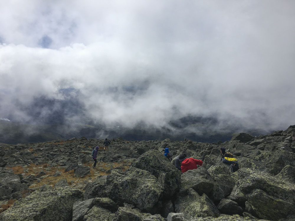 2018_09_WhiteMountainsNH-10245_Edit1000.jpg - Taking a break and watching others come up from the clouds below.  The clouds and fog were beginning to break up slightly.  Like many other mountains in the NH range, Jefferson does not have a smooth summit, it is a talus deposit (also called scree).  Its like a monstrous jackhammer went to work and broke up all that granite, except that that jackhammer is weather and erosion.