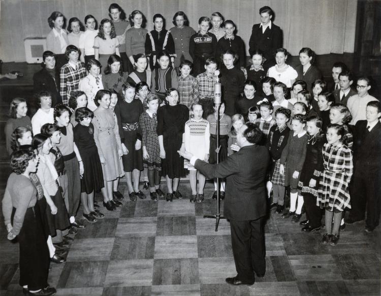 A01_MusicClass.jpg - Can you spot Mom & Ingo?  They are the 4th and 5th from the left, in the front row.  Some comments from Ingo: "The picture is the American Children's Choir in Berlin and the director was Mr. Parker Watkins.  It must have been 1951 or 1952.  I did not remember that picture at all.  Ingrid must have taken it along when she went to the States.  But it brought memories back.  I   even remembered the name of one other girl, which was IngridÕs friend.  I was the only boy among the girls singing soprano.  That was before my voice changed.  Parker Watkins was proud to be a 'Mulatto' and he said that he was a member of the Hall Johnson Choir.  He had quite a temper and hit the keys on the piano like it was a chopping block."Comments on the back of photo read:Pressebild SchubertBerlin-NeutempelhofMussehlstraBe 25Tel. 66 09 35
