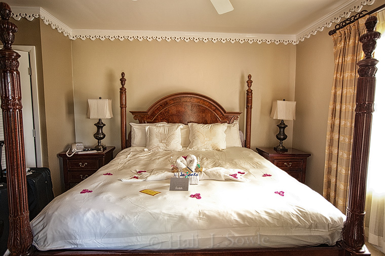 2012_03_25_SandalsLaToc-10005-Edit-750.jpg - It's always nice the first time we get to our room at Sandals.  They always do up the bed so well, here we have the towel swans with our returning guest shirts and our invitation to the returning guest dinner.  There was also a plate with muffins and cookies, but that didn't last too long.