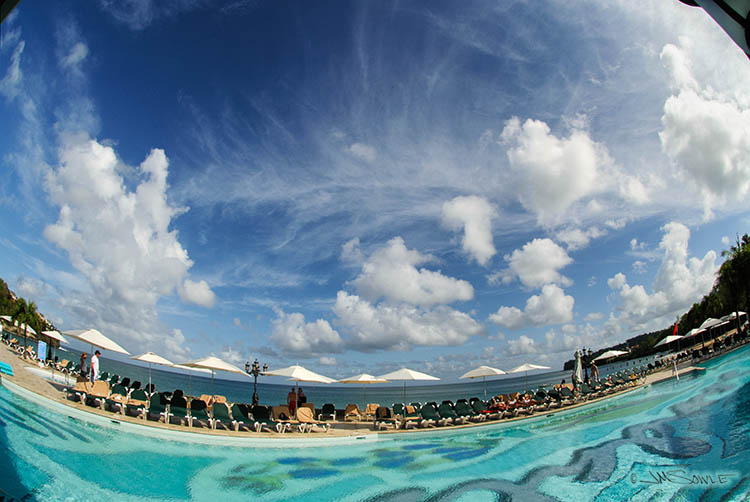 _MIK0462.jpg - The main pool was fun, but a bit loud for our tastes.  Behind the lounge chairs is an eight foot seawall, with stairs leading down to the beach area.  The shot was taken from the buffet dining area.
