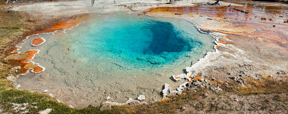 2010_09_27_Yellowstone-10333-37_PanoEdit750.jpg - This hot spring contains high concentrations of silica which has been dissolved from Rhyolite by water which can be over 200 F.  Rhyolite is the most prevalent volcanic rock in Yellowstone.  The dark blue and bright orange areas are where the thermophile bacteria live and grow. The clear areas are where the water erupts from the ground, and it is too hot for these bacteria (meaning the temperature is over 167 F).