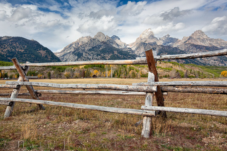 2010_10_07_Yellowstone-10162_63Blend_Edit750.jpg - Peak of a farmhouse in the shadow of the Tetons through a split rail fence.