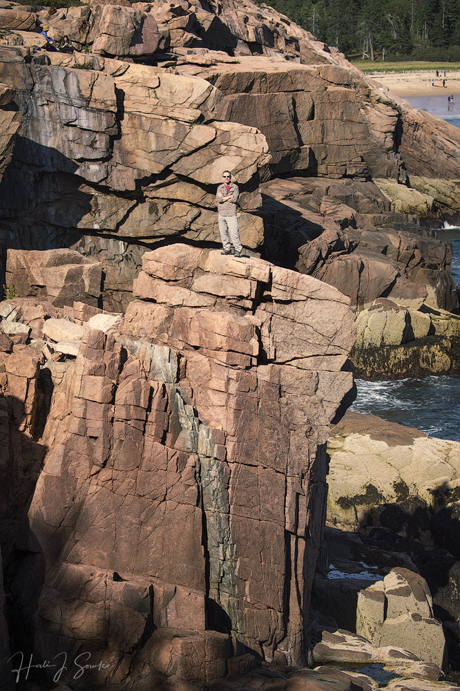 2018_09_Maine-10554-Edit1000.jpg - Mike likes to humor me so when I asked him to walk out along the cliff again so I could get a shot that shows the  geology of the area, he said yes.  This is the beauty and ruggedness of the Maine coast  - the rough hewn, ocean carved blocks of granite, the rough water, the beautiful beach and the evergreen forest in the background.
